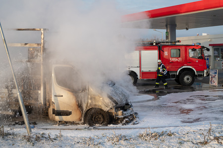 Car fire at the gas station in Orlen, Poland. Burning van and firefighters extinguishing a fire. Season - winter.のeditorial素材