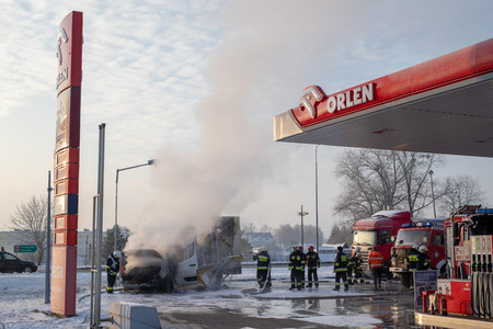 Car fire at the gas station in Orlen, Poland. Burning van and firefighters extinguishing a fire. Season - winter.のeditorial素材