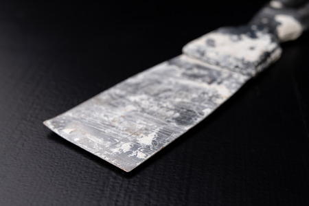A dirty plastering plaster on a workshop table. Tools for construction workers. Black background.