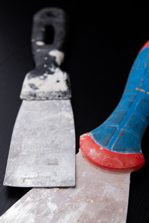 A dirty plastering plaster on a workshop table. Tools for construction workers. Black background.の写真素材