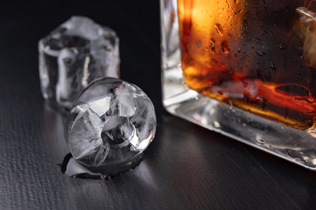 A cold drink with ice on a dark table. A chilled drink in a glass. Black background.の写真素材