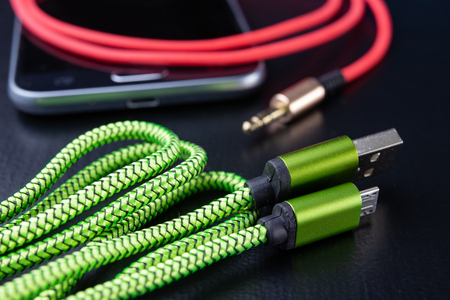 Jack and usb cable for smartphone. Telephone and accessories on the table. Dark background.の写真素材