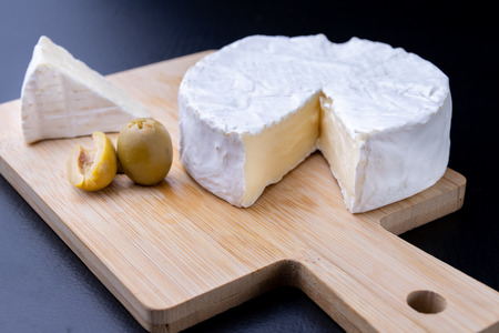 Tasty blue cheese on a wooden board. Prepared Italian dishes on the kitchen table. Dark background.の写真素材