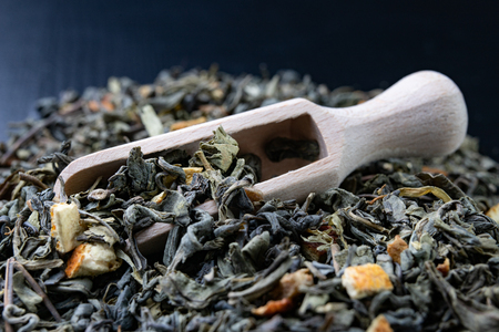 Tea in leaves and wooden whiskers. A blend of the best varieties of tea. Dark background.の写真素材
