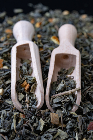 Tea in leaves and wooden whiskers. A blend of the best varieties of tea. Dark background.の写真素材