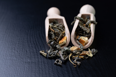 Tea in leaves and wooden whiskers. A blend of the best varieties of tea. Dark background.の写真素材