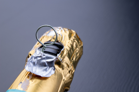 Closed bottle of champagne on the kitchen table. Opening a new bottle of noble beverage. dark background.の写真素材