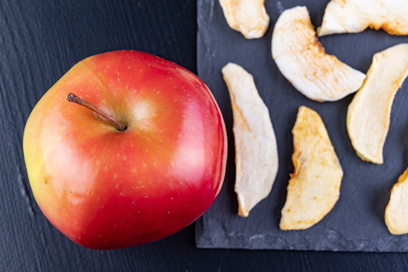 Tasty pieces of dried apples on the kitchen table. Delicious sweet additions to desserts. Dark background.の写真素材