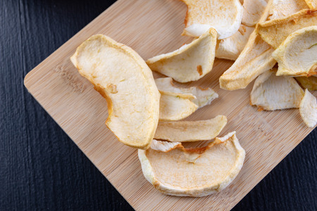 Tasty pieces of dried apples on the kitchen table. Delicious sweet additions to desserts. Dark...