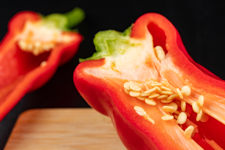Ripe red paprika on a wooden board. Healthy vegetables in a home kitchen. Dark background.の写真素材