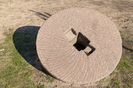 A stone wheel for grinding grain. Old mill grinders. Place - a monument in a local village. Season winter.の写真素材