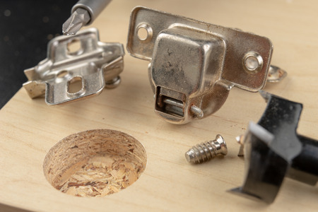 Milling the hole for the can hinge. Joinery works when assembling chipboard furniture. light background.の写真素材
