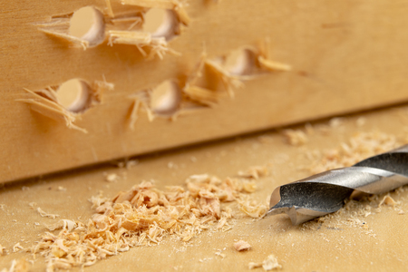 Drilling a hole in wood. Wood drill and plywood in a carpentry workshop. Light background.の写真素材
