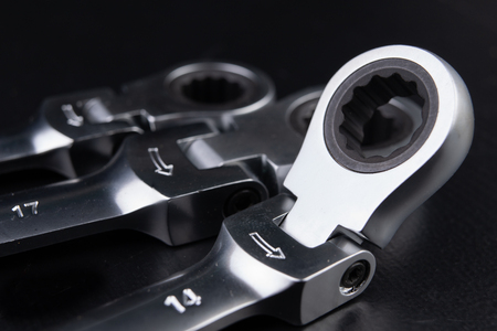 New chrome-plated key ring with latch. Accessories for a mechanic on a workshop table. Dark...