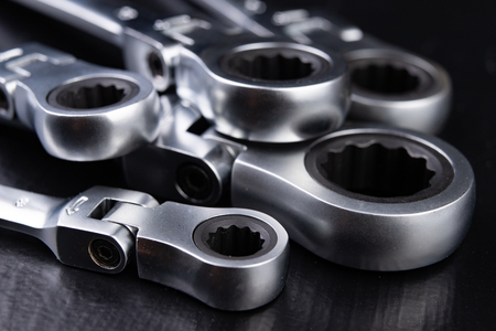 New chrome-plated key ring with latch. Accessories for a mechanic on a workshop table. Dark...