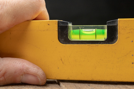 Measuring the slope of a surface using a spirit level. Measuring accessories for mechanics. Dark...