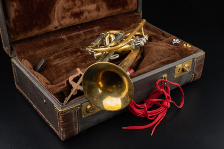 Old covered patina trumpet in a case. A historic wind musical instrument and a suitcase. Dark background.の写真素材