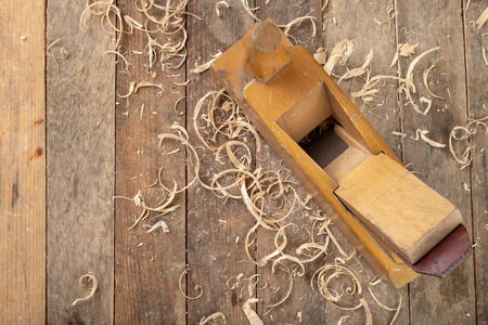 Old planer on a wooden carpentry table. DIY accessories in an old workshop. Dark background.の写真素材