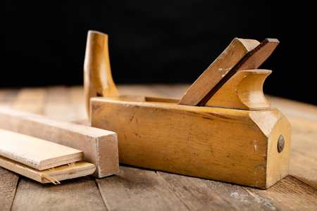 Old planer on a wooden carpentry table. DIY accessories in an old workshop. Dark background.の写真素材