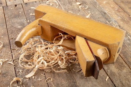 Old planer on a wooden carpentry table. DIY accessories in an old workshop. Dark background.