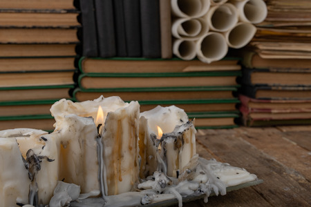 Burned candle on the background of old books. Desk of an old writer. Dark background.の写真素材