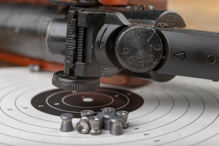 A pneumatic weapon on a wooden table on a shooting range. Shooting accessories needed for shooting sports. Dark background.の写真素材