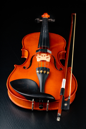 Beautiful new shiny violin on a dark table. Musical string instrument prepared for work. Dark background.の写真素材