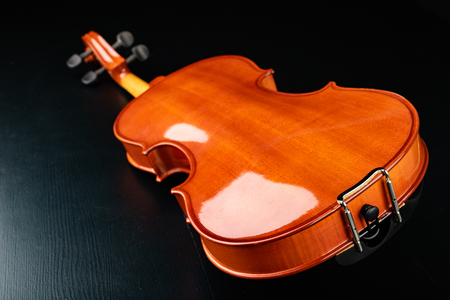 Beautiful new shiny violin on a dark table. Musical string instrument prepared for work. Dark background.の写真素材