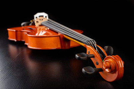 Beautiful new shiny violin on a dark table. Musical string instrument prepared for work. Dark...