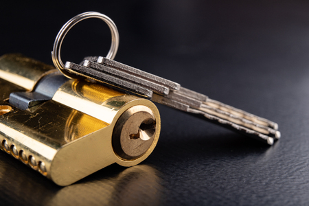 A new door lock on a dark background. A patent and keys to secure the front door. A black background.