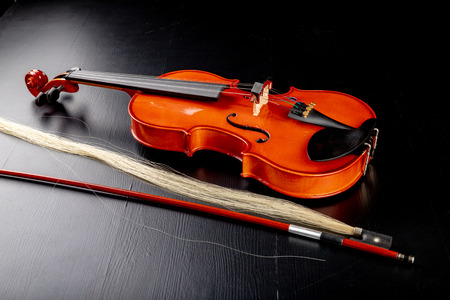 Broken bow to the violin. Damaged musical instrument. Dark background.の写真素材