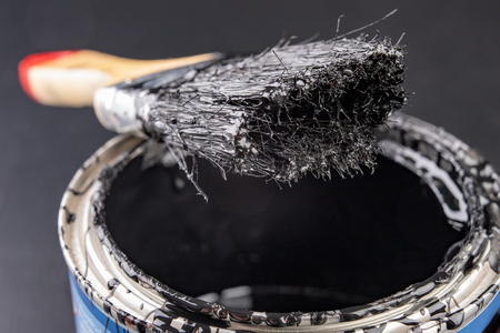 Old paint brush and metal can with paint. Accessories for painting oil paint dirty with black paint. Dark background.の写真素材