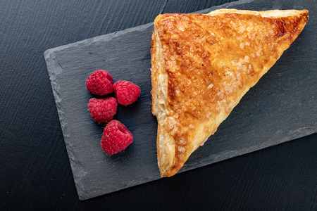 Tasty cake with shortcrust pastry with fruit. Fresh raspberries and cake on gray paper. Dark background.の写真素材