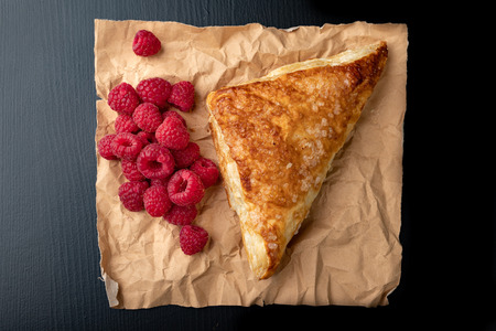 Tasty cake with shortcrust pastry with fruit. Fresh raspberries and cake on gray paper. Dark background.の写真素材