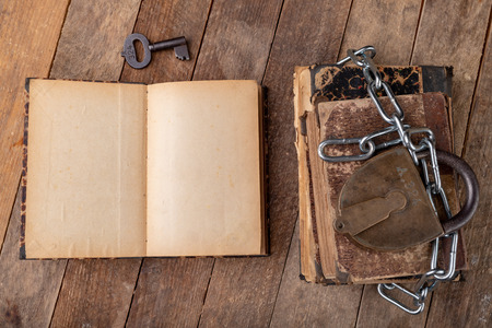 Old books bound by a new shiny chain with an old padlock. Forbidden old works artists on a wooden...
