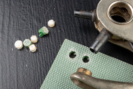 Work in an old craft workshop. Making holes in the skin and other materials. Dark background.の写真素材