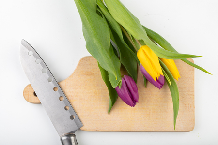 A bouquet of flowers on the kitchen table. Wooden chopping board, knife and kvass. Light background.の写真素材