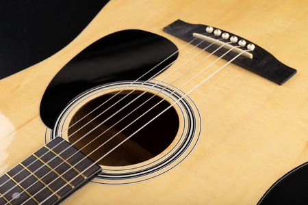 Classical guitar on a dark wooden table. Musical instrument stringed. Black background.