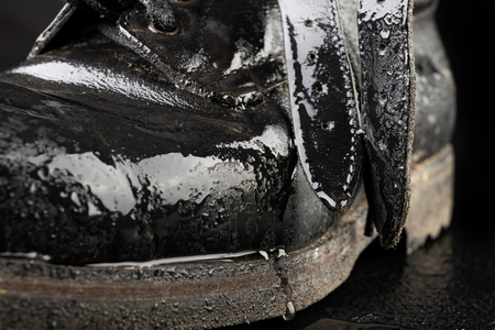 Old black army boots wet from the rain. Footwear resistant to difficult terrain conditions. Dark...