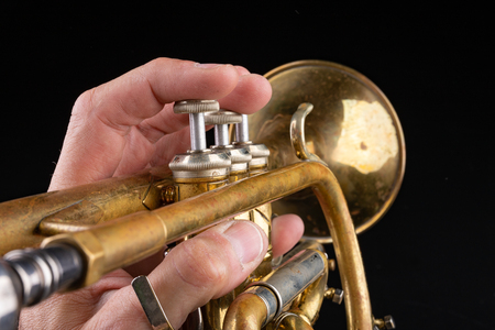 Old trumpet on a dark wooden table. Wind instrument in the old style. Black background.の写真素材