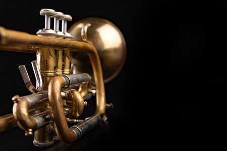 Old trumpet on a dark wooden table. Wind instrument in the old style. Black background.の写真素材