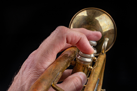 Old trumpet on a dark wooden table. Wind instrument in the old style. Black background.の写真素材