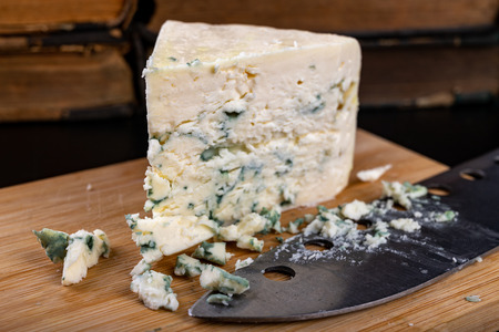 Delicious blue puff cheese on a wooden board. Tasty pleasing cheese prepared for a meal. Dark...