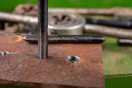Manual thread cutting in metal. Locksmith accessories for small work in the home workshop. Dark...