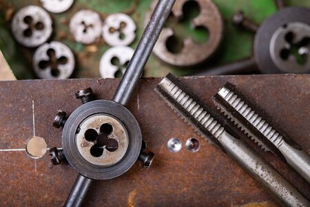 Manual thread cutting in metal. Locksmith accessories for small work in the home workshop. Dark...