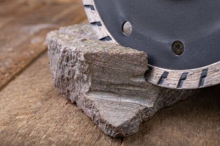 Stone cutting with a diamond disc mounted in a grinder. Work in a stone workshop. Dark background.
