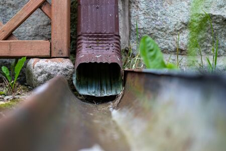 An old gutter in a detached house. Rainwater drainage from the roof. Season of the summer.