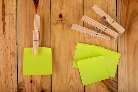 Colorful sticky notes hung on wooden clips. Sticky notes for saving reminders on a wooden table. Light background.の写真素材