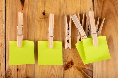 Colorful sticky notes hung on wooden clips. Sticky notes for saving reminders on a wooden table. Light background.の写真素材