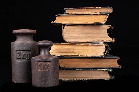Old kilo weights on books. Old books and weighing machines. Dark background.の写真素材